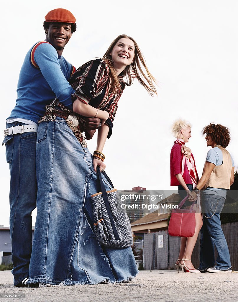 Two Young Couples Stand in an Urban Setting, Laughing and Talking