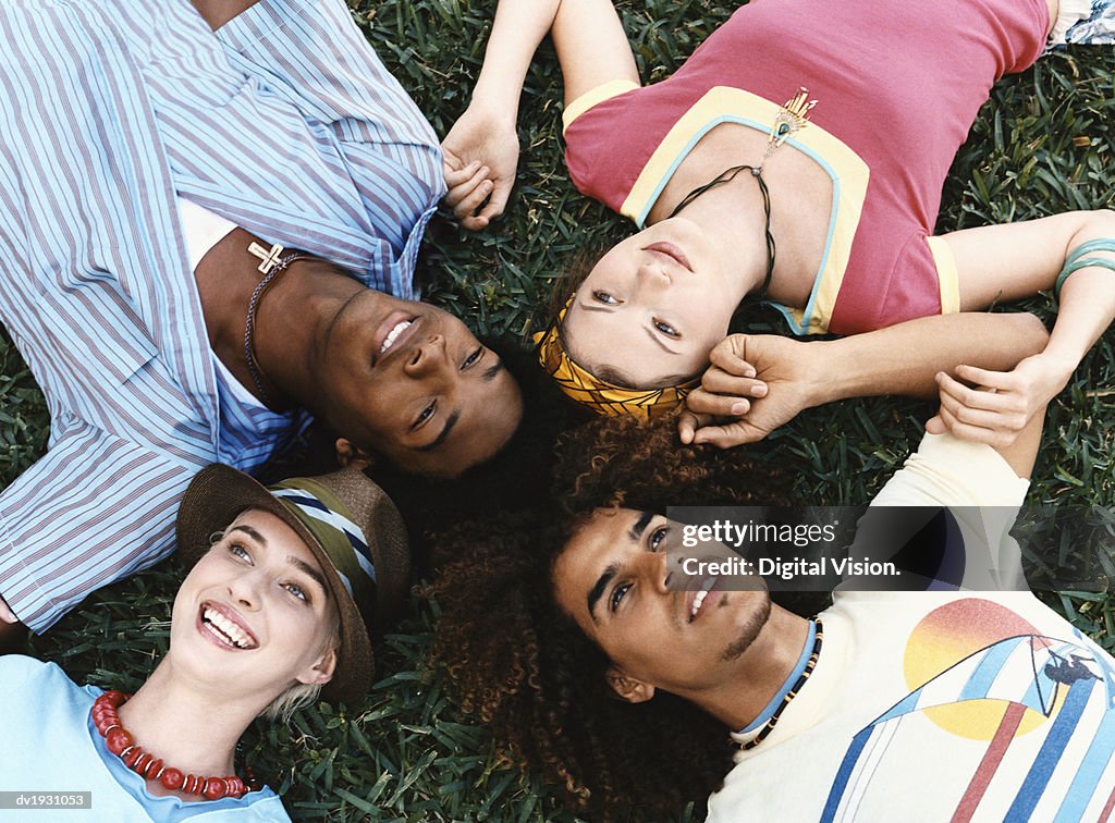 Small Group of Twentysomething Men and Women Lying Together on Grass