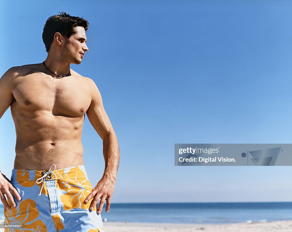 Man Standing on a Beach With His Hands on His Hips and Looking Sideways