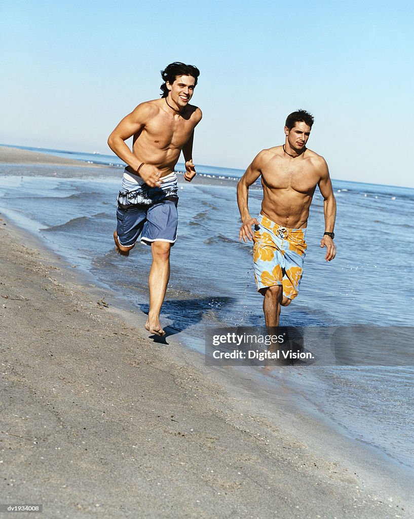 Two Men Running on the Beach at the Water's Edge