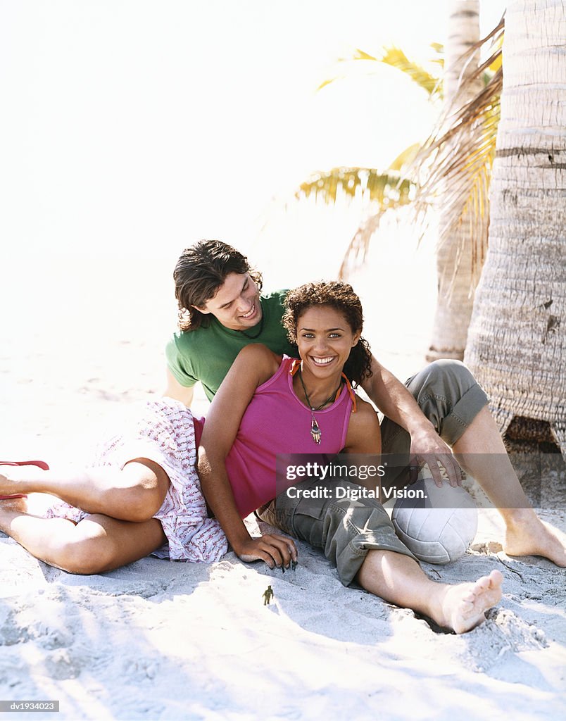 Portrait of a Young Woman Sitting by a Palm Tree With a Young Man