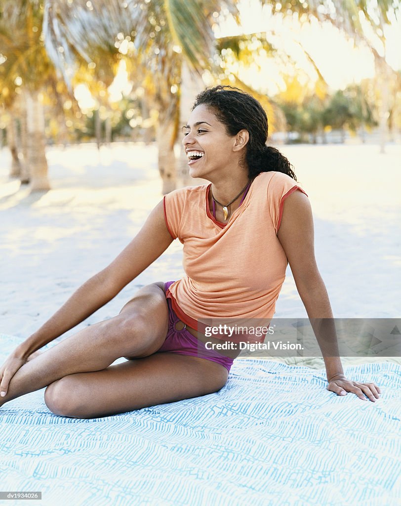 Young Woman Laughing and Sitting on a Beach