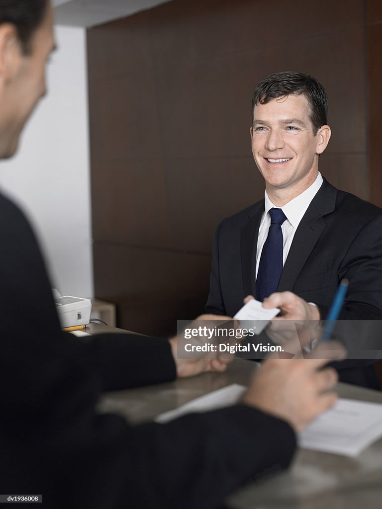 Businessman Passes a Business Card at a Reception Desk