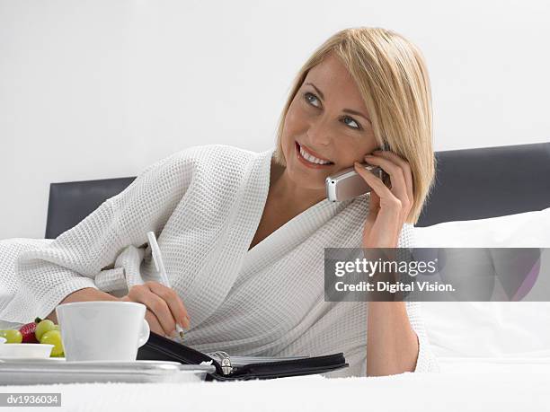 businesswoman in a dressing gown lying on a bed and using a mobile phone - dressing up ストックフォトと画像