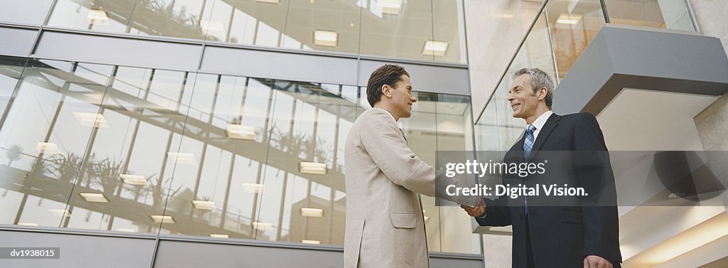 Two Businessmen Shaking Hands Standing Outside an Office Building