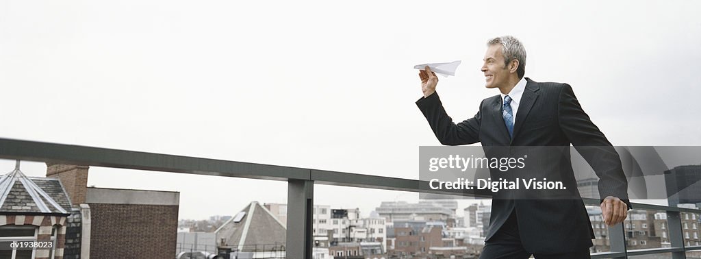 Businessman Throwing a Paper Plane From the Rooftop of a Building