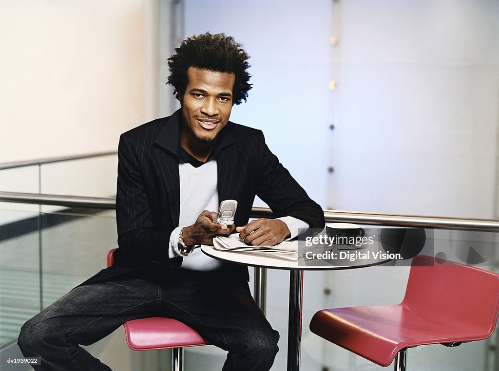 Businessman Sits at a Table Using His Mobile Phone