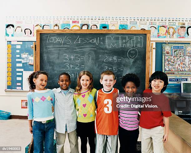 portrait of primary schoolboys and schoolgirls standing in a line in a classroom - primaria fotografías e imágenes de stock