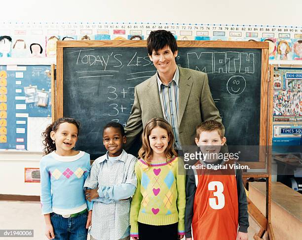 portrait of a teacher with primary school children in a classroom - portrait of teacher and student stock pictures, royalty-free photos & images