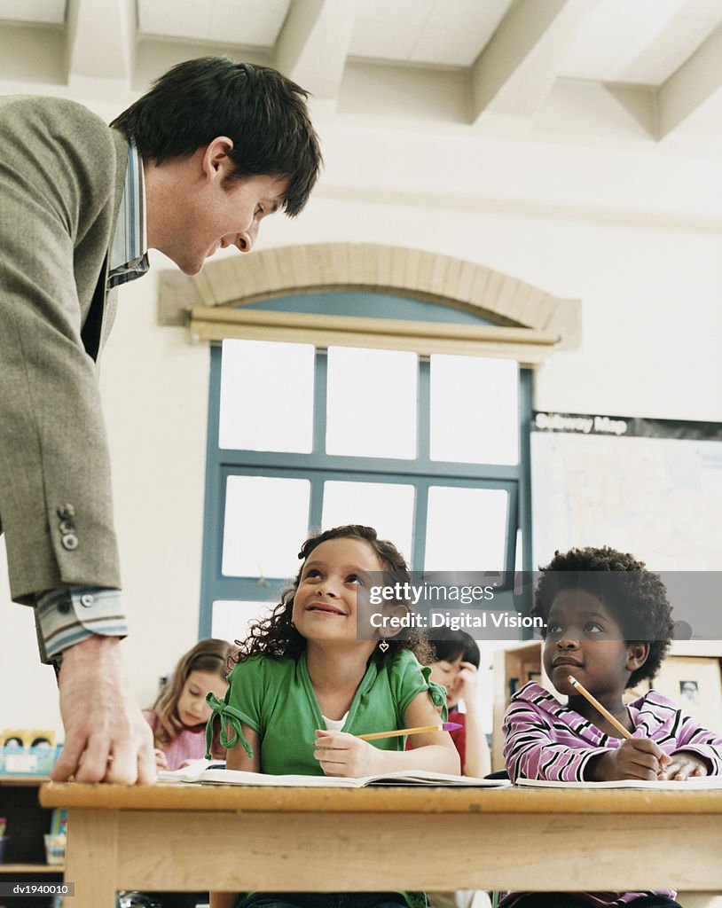 Teacher in a Classroom Helping Primary School Children