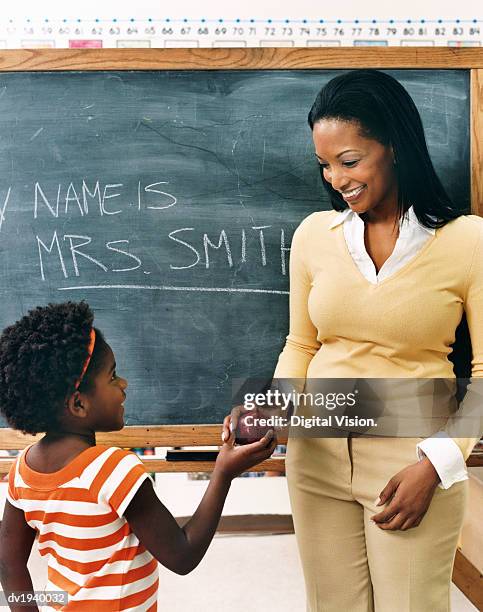 young schoolgirl giving an apple to her teacher - child giving gift stock pictures, royalty-free photos & images