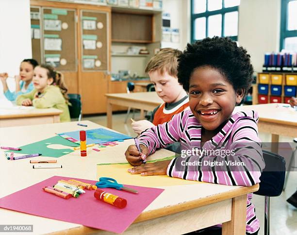 primary school children sitting at their desks colouring-in - colouring stockfoto's en -beelden