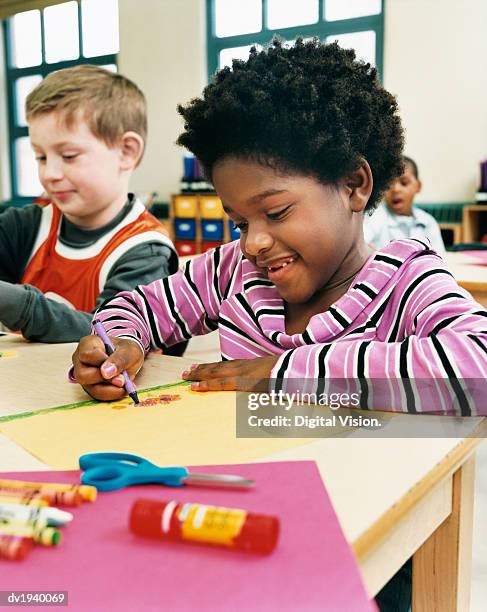 primary school girl and boy sitting at their desks colouring-in - colouring ストックフォトと画像