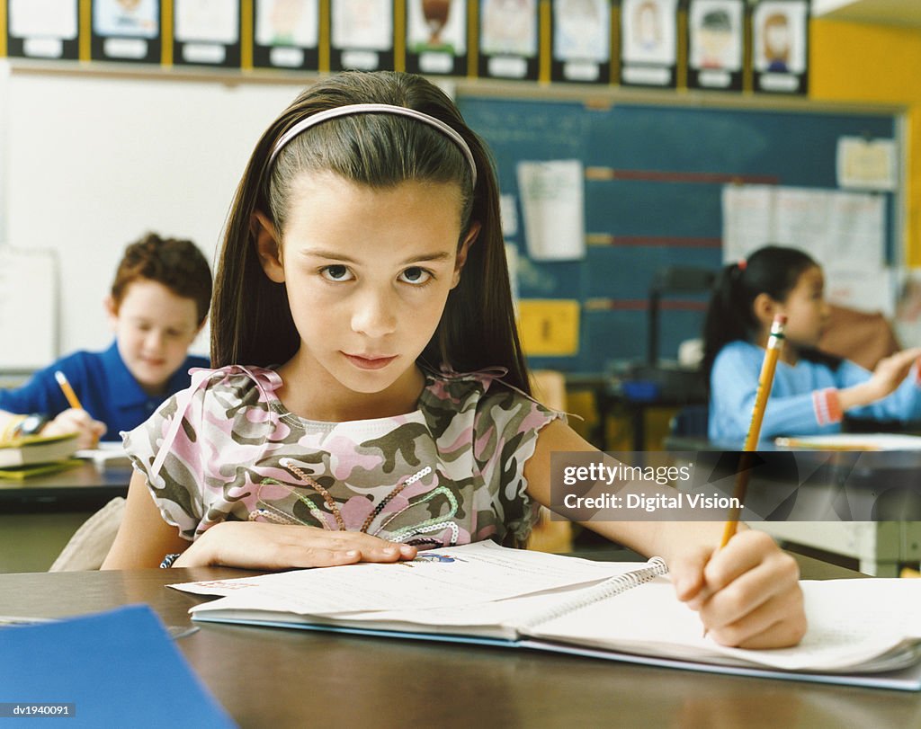 Portrait of a Schoolgirl Writing in Her Exercise Book in a Classroom