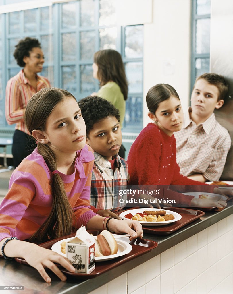 Four Schoolboys and Schoolgirls Looking Displeased With the Food on Their Trays