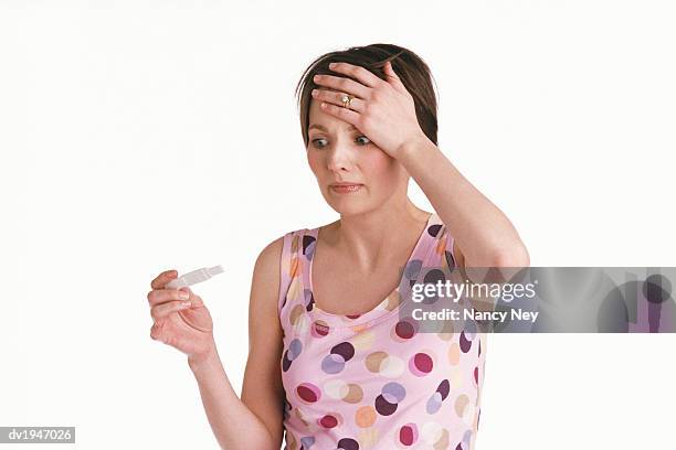 young woman looks at a pregnancy test, her hand on her head in panic - hand on head foto e immagini stock