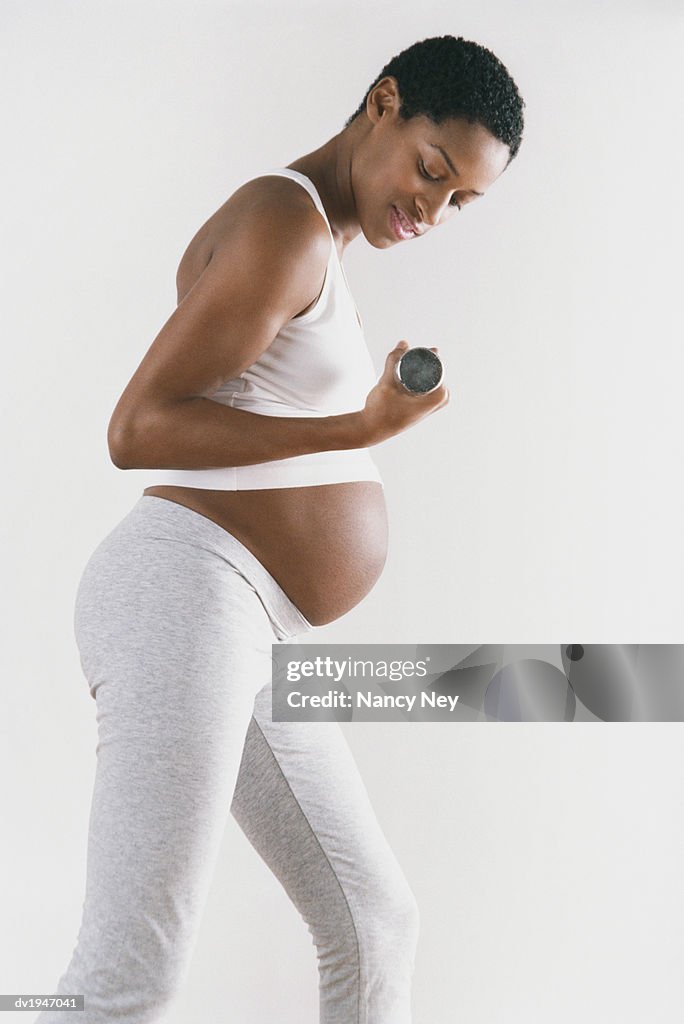 Studio Shot of a Pregnant Woman Lifting a Dumbbell