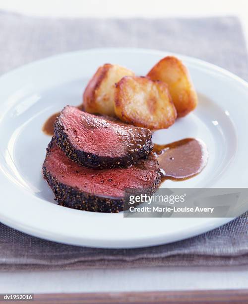 slices of roast beef with roast potatoes and gravy - avery stock pictures, royalty-free photos & images