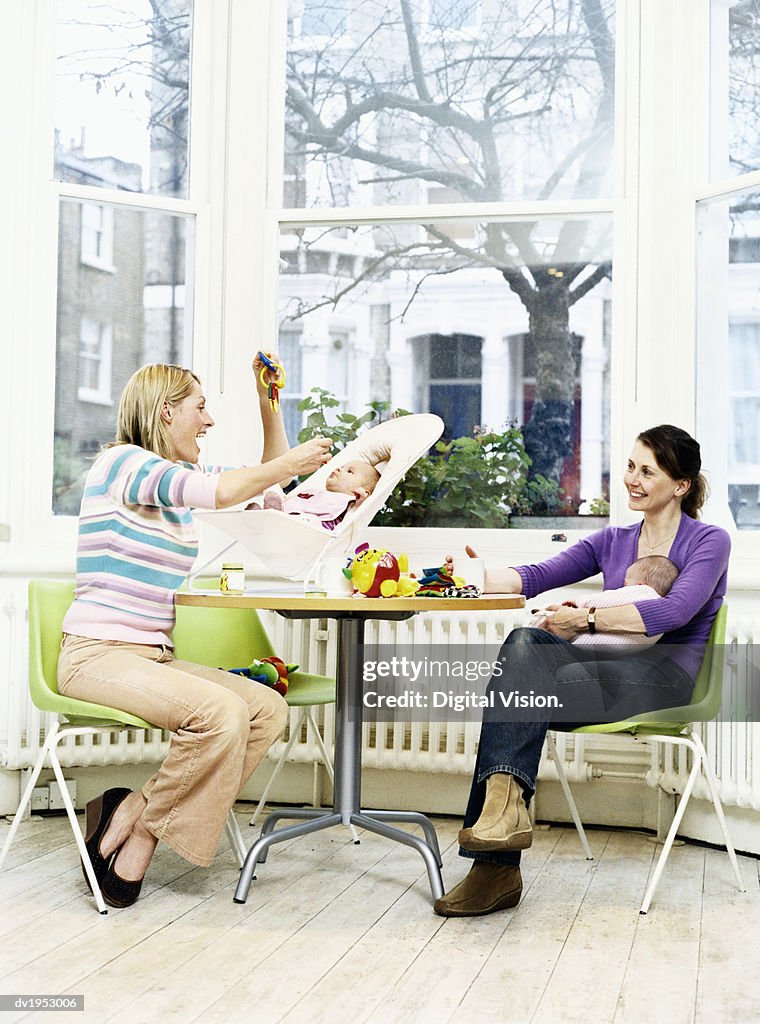 Two Mothers With Their Offspring Sitting at a Table