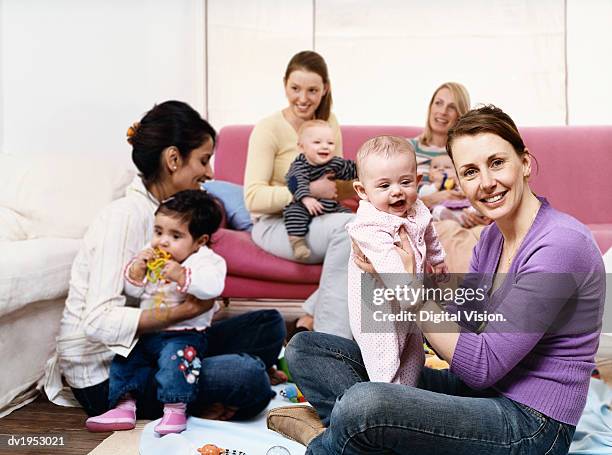 young mothers playing with babies in a living room - play date imagens e fotografias de stock