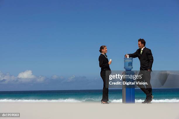 businessman and businesswoman standing and taking by a water cooler on a beach - digital devices beside each other bildbanksfoton och bilder