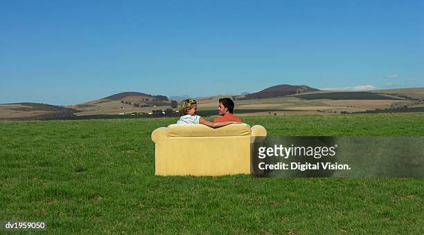 rear view of a couple sitting on a sofa and looking at each other face to face in the open countryside - open seat godo stock-fotos und bilder