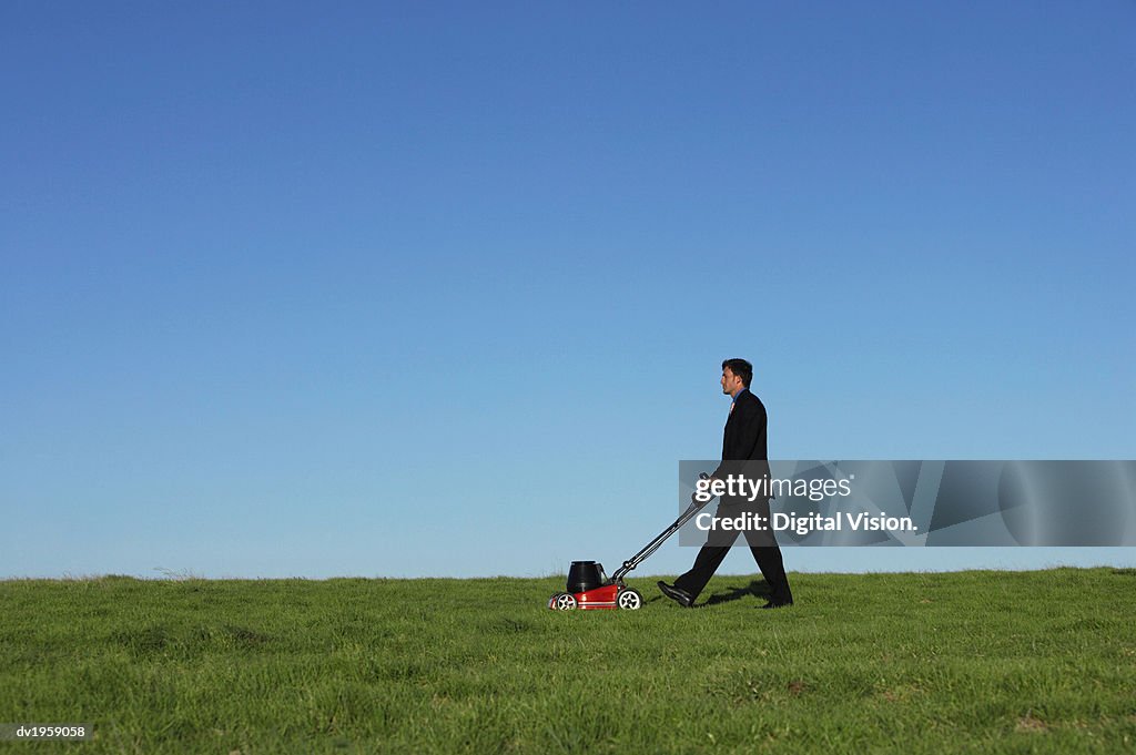 Businessman Pushing a Lawnmower Over Grass