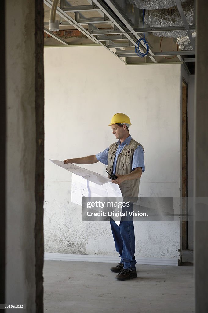Foreman Stands in a Building Site Examining a Blueprint