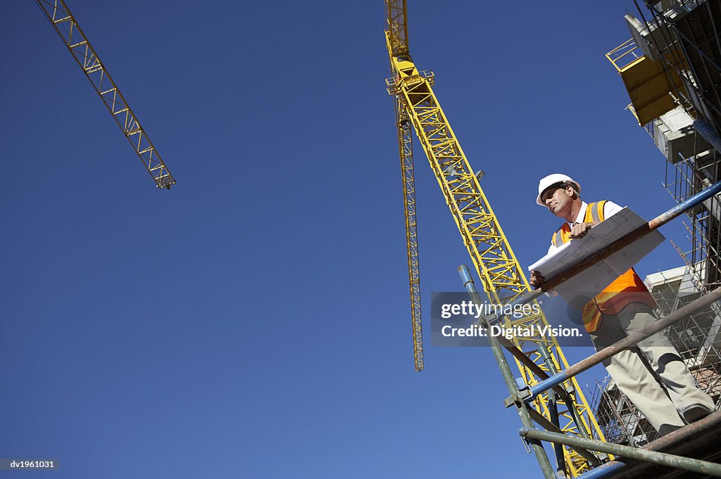 Well Dressed Man Standing on a Scaffolding Platform Holding Blueprints