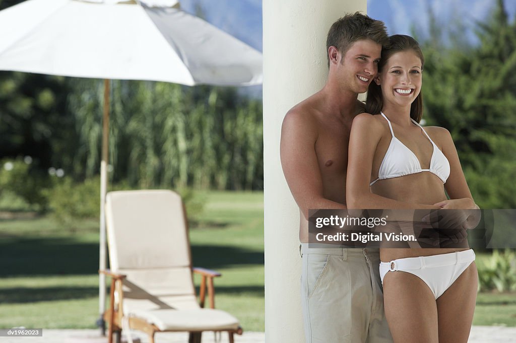 Young Couple in Swimwear Stand on a Porch, Embracing