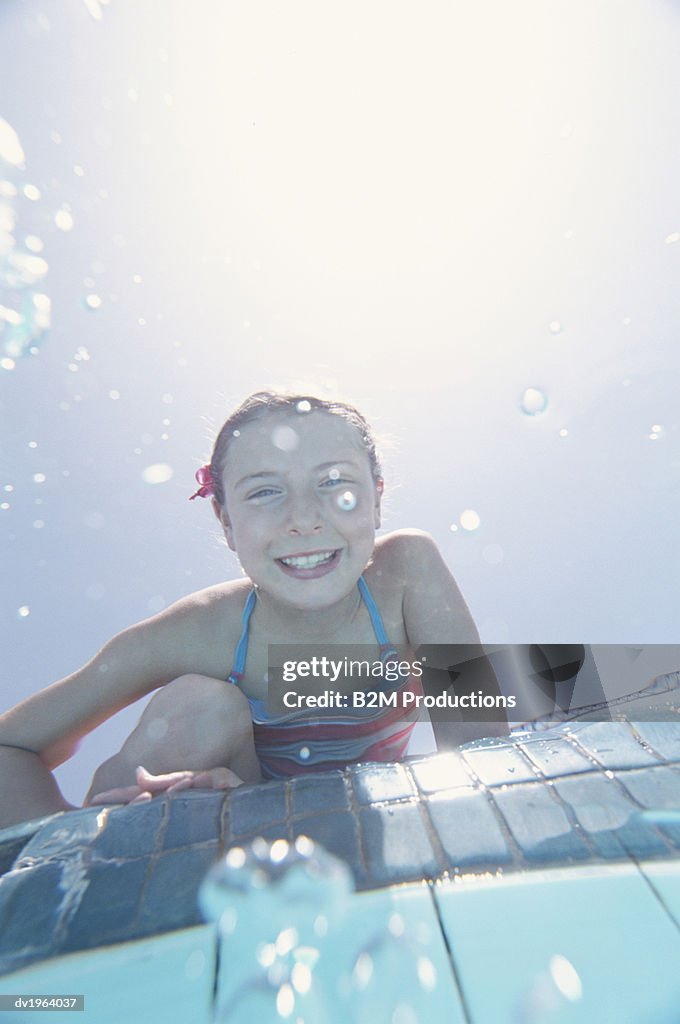 Smiling Girl Sitting on the Edge of a Swimming Pool
