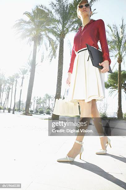 confident businesswoman walks down an avenue carrying a clipboard - down blouse imagens e fotografias de stock