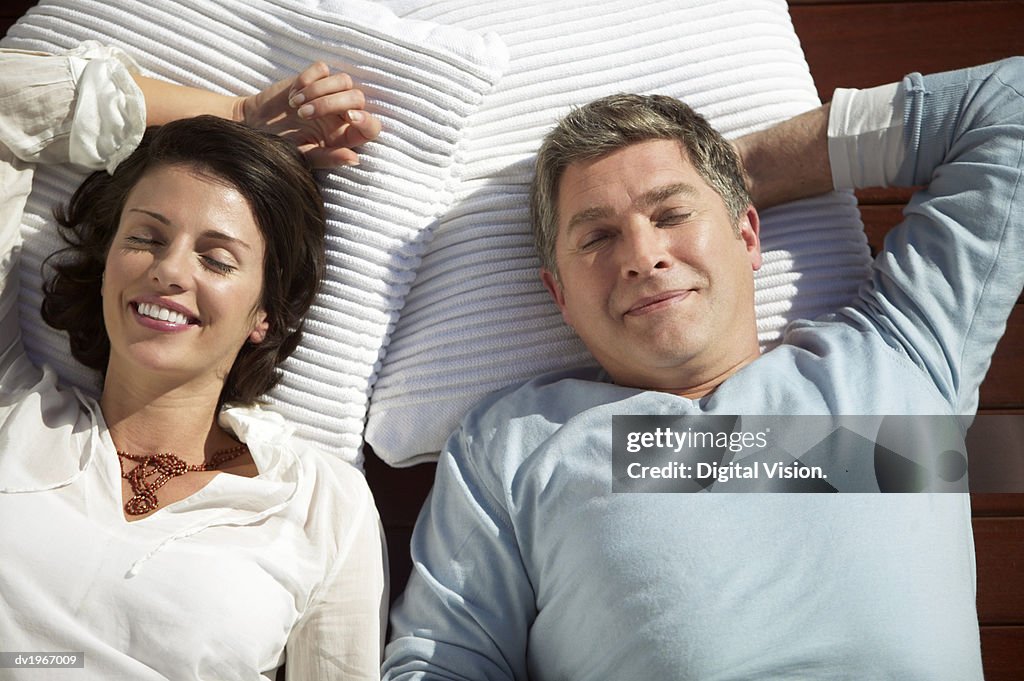 Couple Lie Side by Side on Towels, Sunbathing With Their Eyes Closed