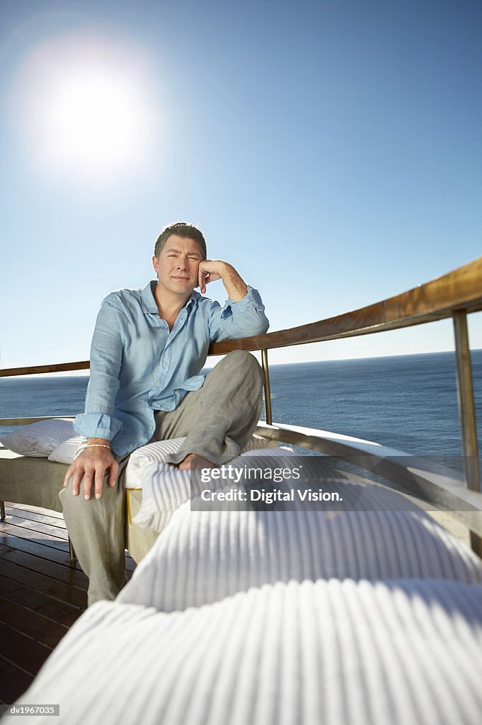 Pensive Man Sits on a the Bench of a Sunny Balcony