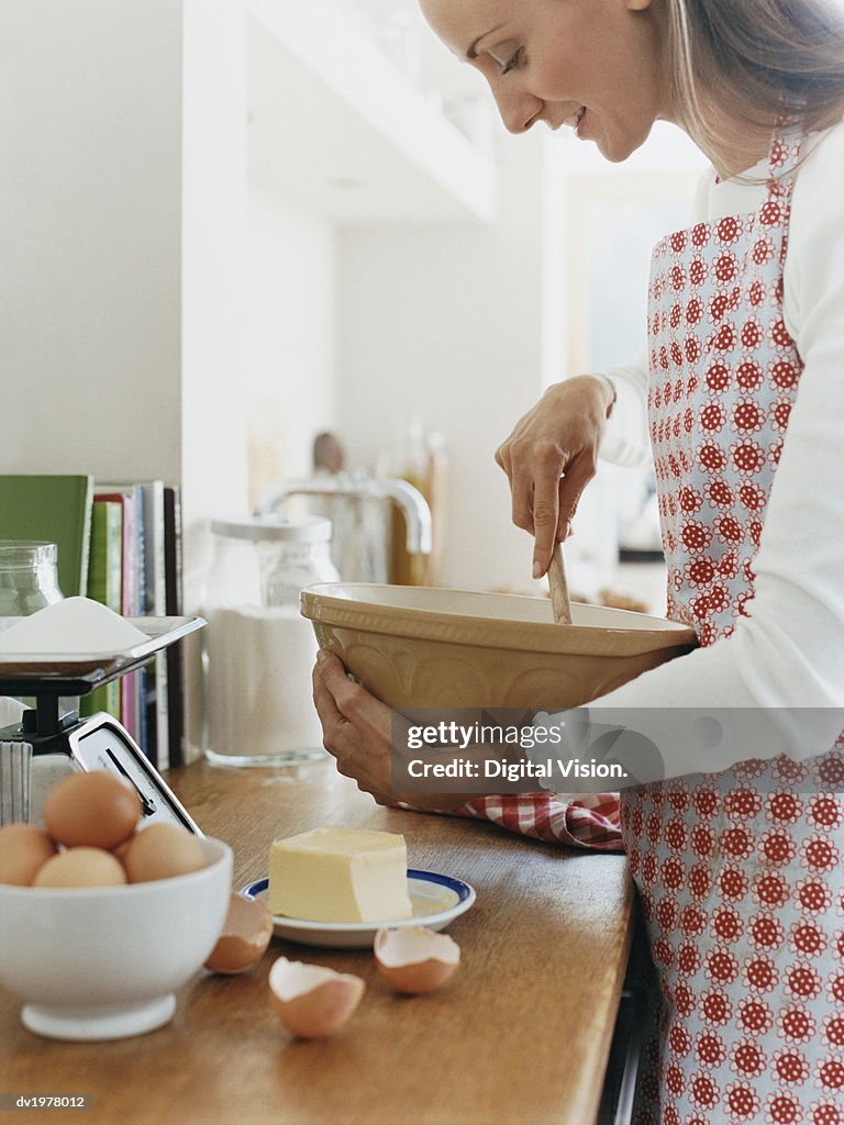 Woman Holding a Bowl and a Wooden Spoon in a Kitchen