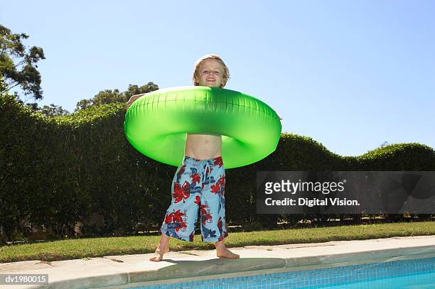 portrait of a young boy wearing a rubber ring standing by a swimming pool - rubber ring - fotografias e filmes do acervo
