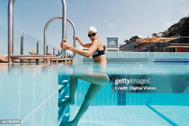 young woman standing on steps at the edge of a swimming pool - portrait of young woman standing against steps imagens e fotografias de stock