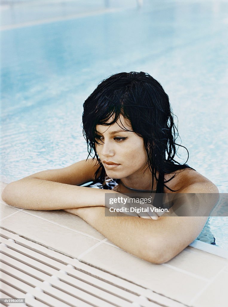 Young Woman With Her Arms Crossed at the Edge of a Swimming Pool