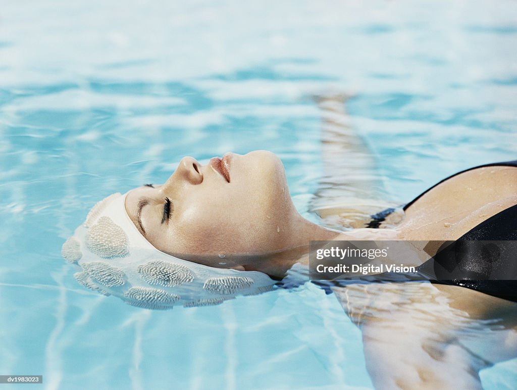 Young Woman Lying Afloat in a Swimming Pool With Her Eyes Closed