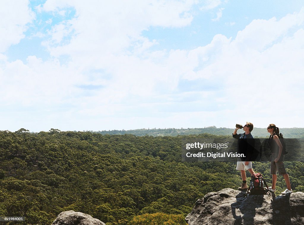 Hiking Couple Stand on a Rock Looking at the View of the Countryside