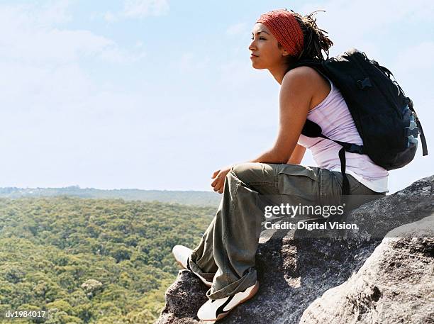 woman sitting on rock looking at view - pantaloni militari foto e immagini stock