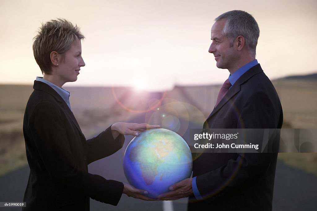 Two Business Executives Standing Face to Face and Holding a Globe