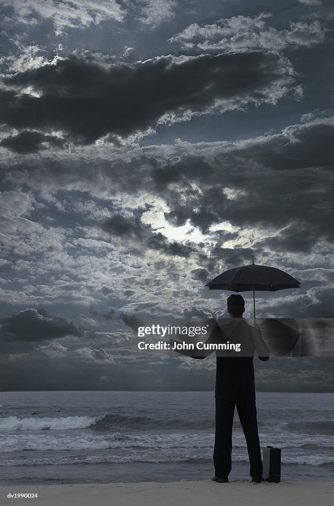 Silhouetted Businessman Standing on a Beach at Night, Holding an Umbrella and Checking for Rain