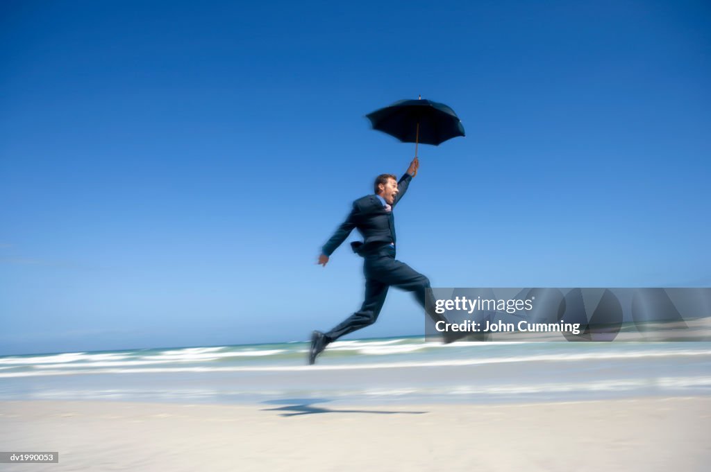 Blurred Motion Shot of a Care Free Businessman Jumping in Mid Air, on a Beach