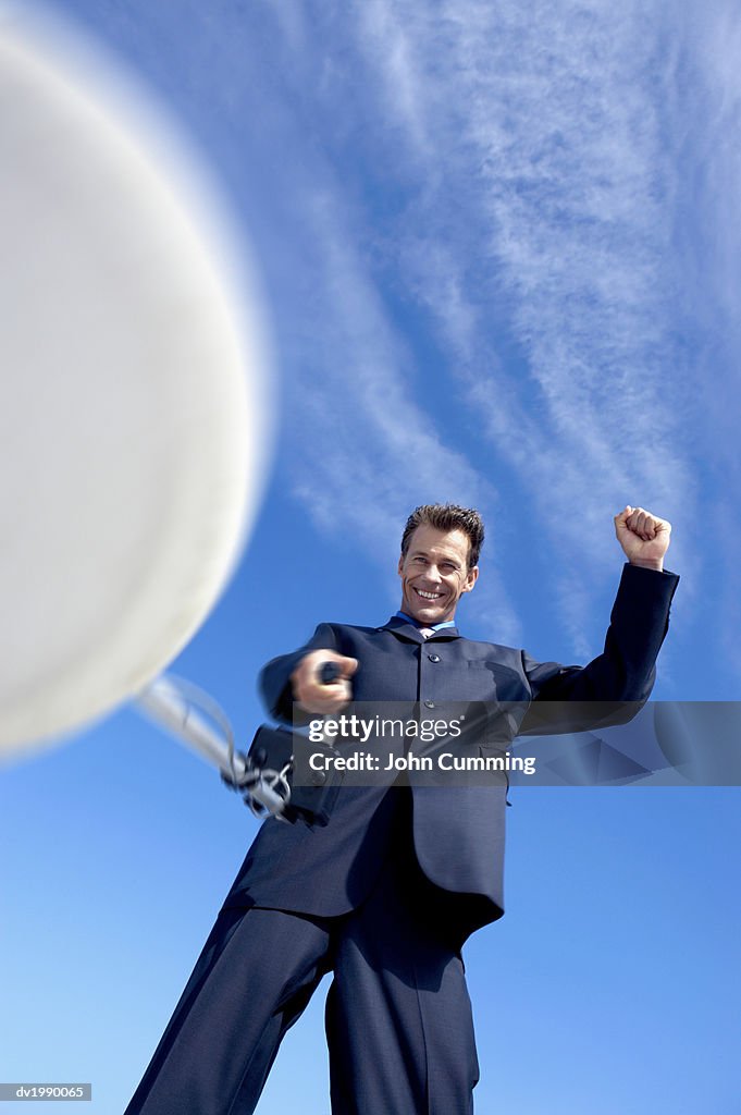 Businessman Holding a Satellite Dish With His Fist in the Air