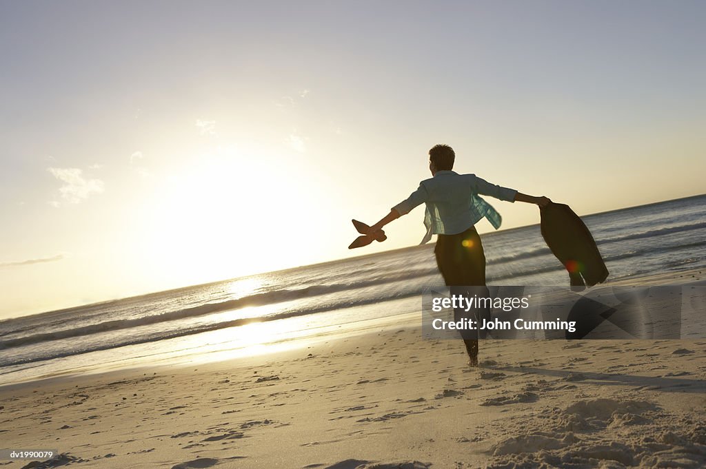 Businesswoman Running Barefoot on the Beach Towards the Sea