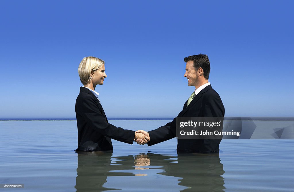 Two Business Executives Shaking Hands and Standing in the Sea