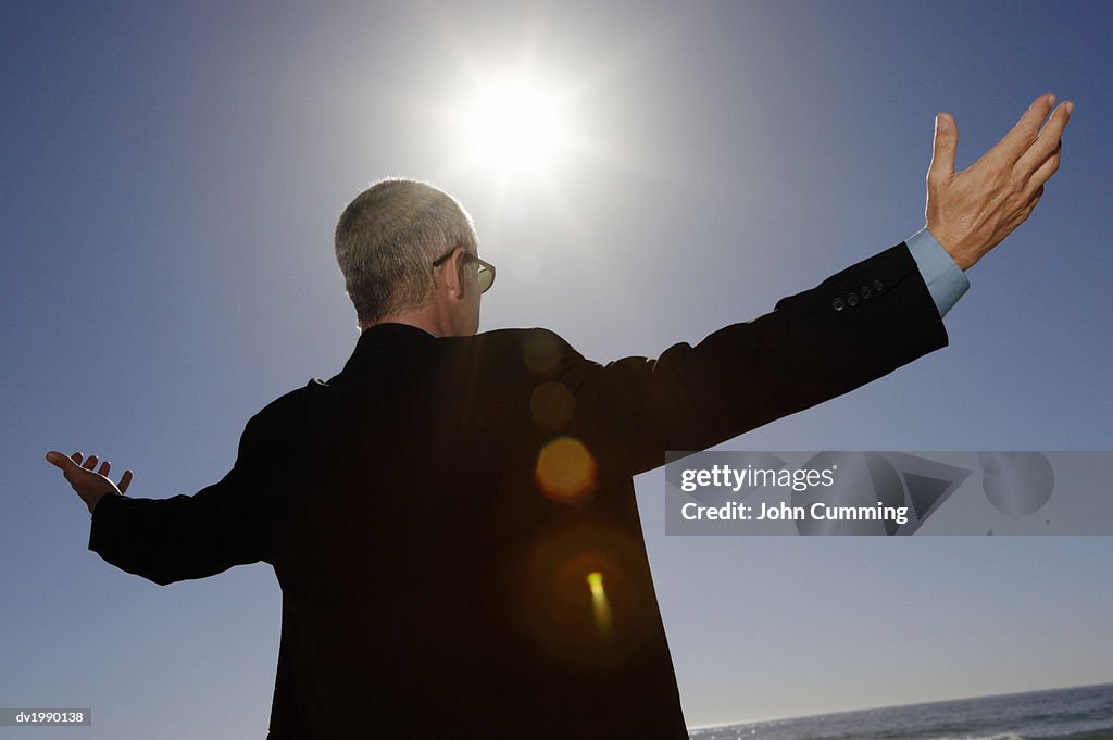 Businessman Standing Below Bright Sunlight With His Arms Out