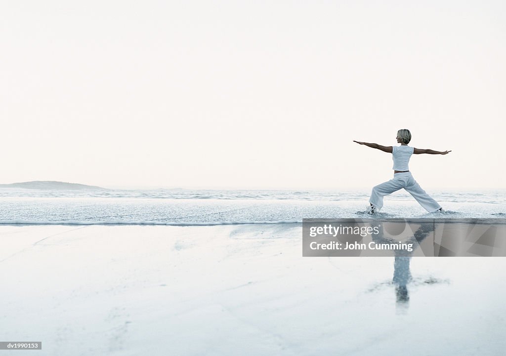 Woman Stands on the Beach at the Water's Edge, Exercising