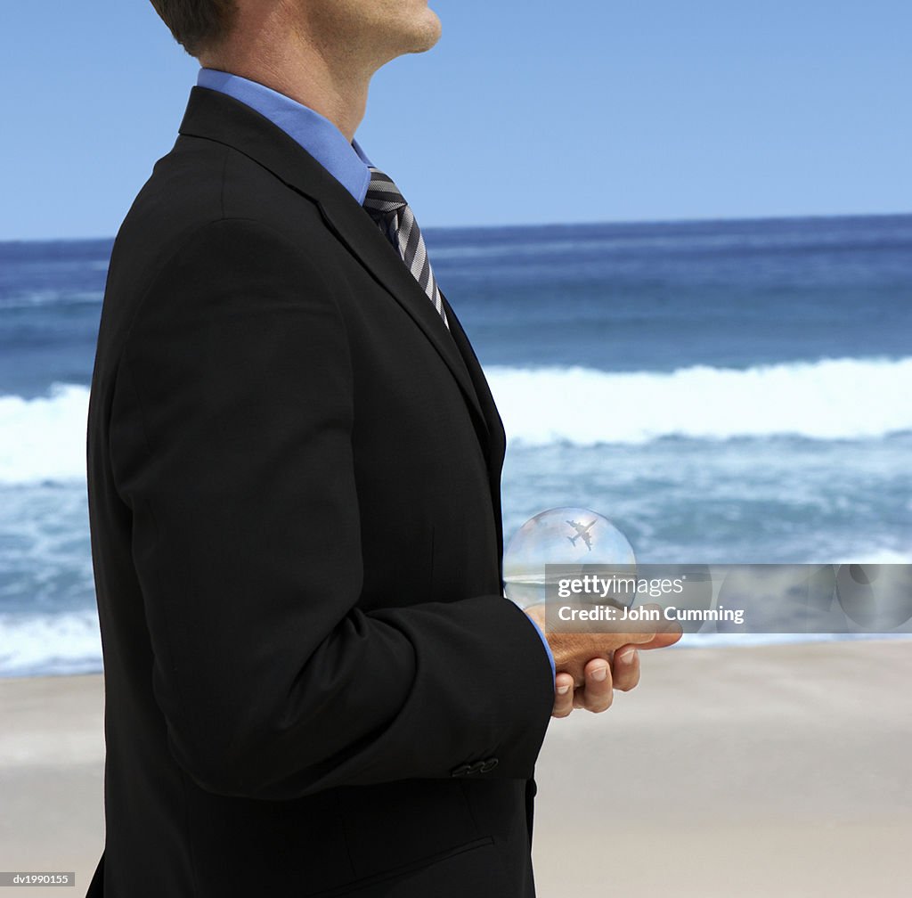 Mid Section View of a Businessman Holding a Crystal Ball on a Beach